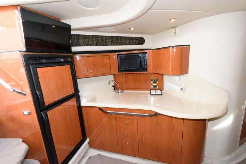 Slide: The Image of 1999 Sea Ray 380 Sundancer yacht kitchen with wood cabinetry, microwave, and refrigerator. - 15