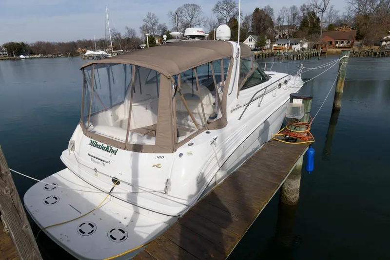 Slide: The Image of 1999 Sea Ray 380 Sundancer docked at a marina, featuring a beige canopy. - 3