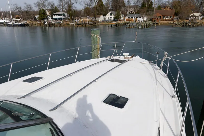 Slide: The Image of 1999 Sea Ray 380 Sundancer yacht docked by a serene waterfront with houses in the background. - 5