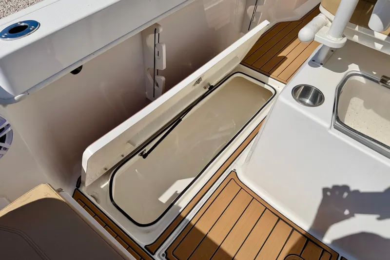 Slide: The Image of 2023 Bayliner Trophy T24CC boat storage compartment with teak flooring and cup holder. - 30