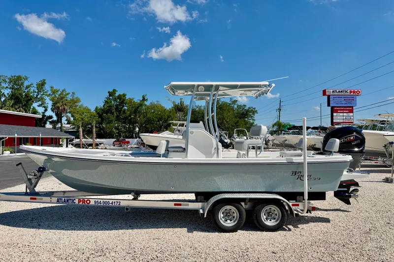 The Image of 2026 Bay Rider 239 Bay boat on trailer at dealership under clear blue sky. - 0