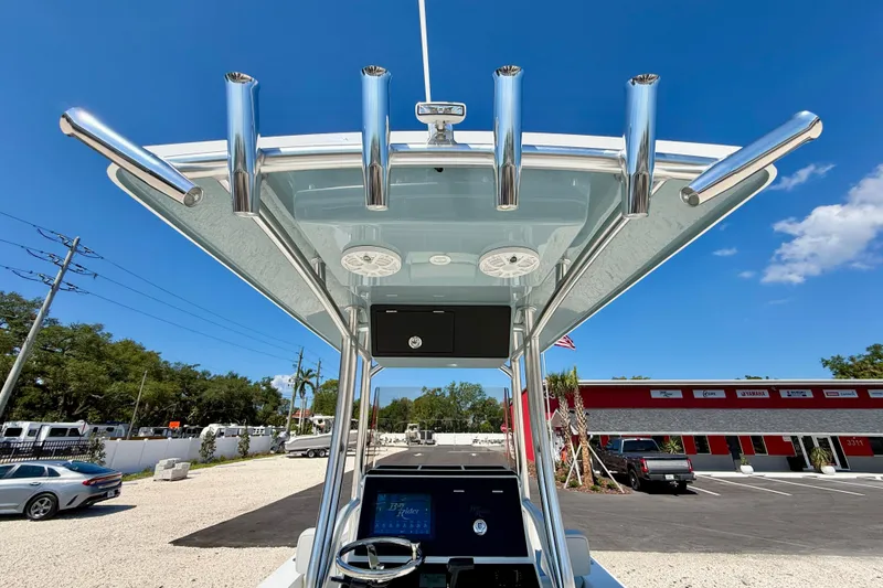 Slide: The Image of 2026 Bay Rider 239 Bay boat with T-top and rod holders, parked outdoors under clear blue sky. - 29