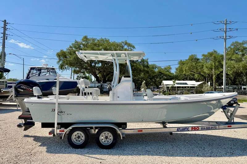 Slide: The Image of 2026 Bay Rider 239 Bay boat on trailer, displayed outdoors under clear blue sky. - 4