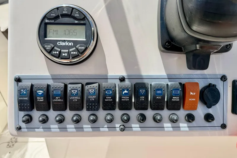 Slide: The Image of Control panel of a 2024 Key West 239 DFS boat with various switches and a Clarion radio. - 16
