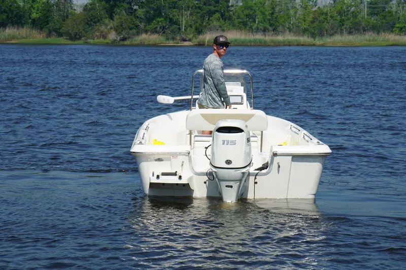 Slide: The Image of 2020 Bulls Bay 2000 boat on water with person steering, surrounded by trees. - 2