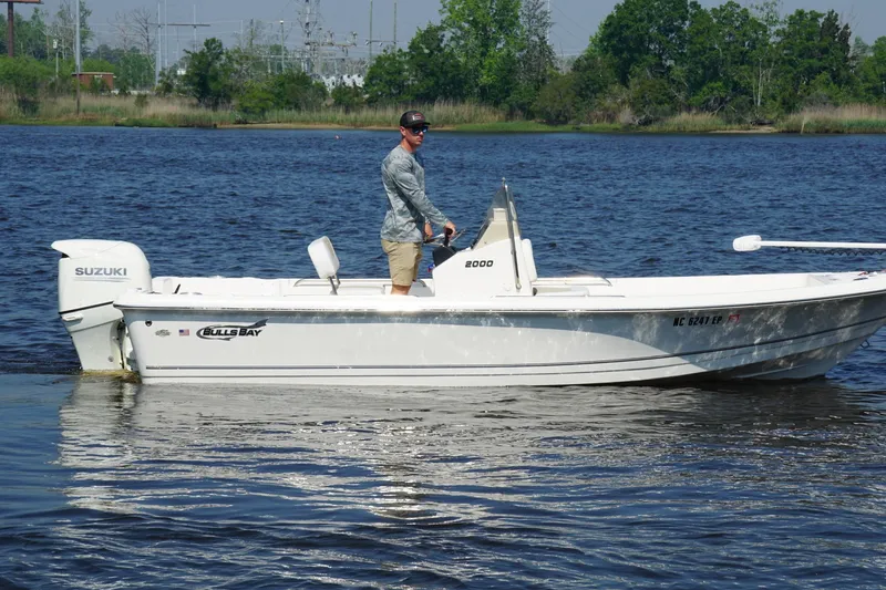 Slide: The Image of Man operating a 2020 Bulls Bay 2000 boat on a calm lake. - 3