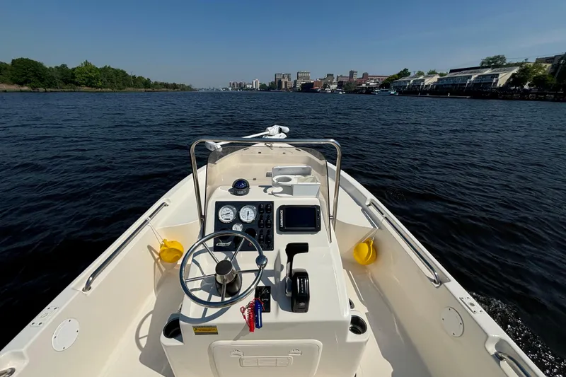 Slide: The Image of Bulls Bay 2000 boat, 2020 model, navigating a scenic river with city skyline. - 8