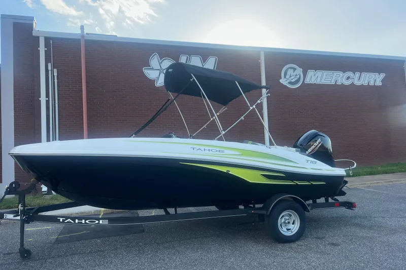 The Image of 2023 Tahoe T18 boat with Mercury engine on trailer, parked outside a brick building. - 0