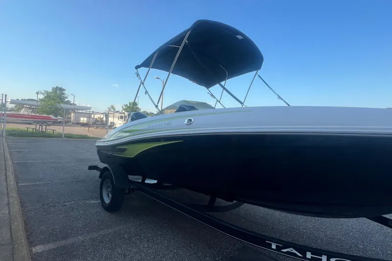 Slide: The Image of 2023 Tahoe T18 boat with canopy on trailer, parked outdoors under clear sky. - 25