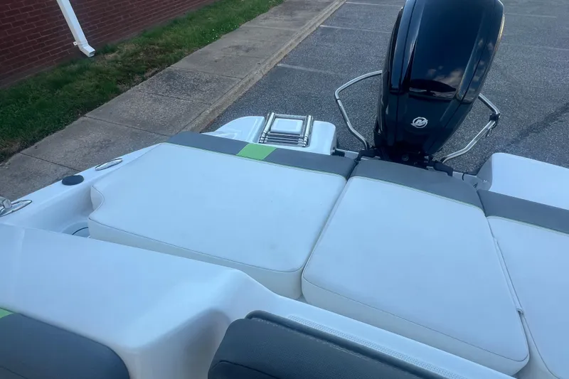 Slide: The Image of 2023 Tahoe T18 boat with cushioned seating and outboard motor, parked on pavement. - 37