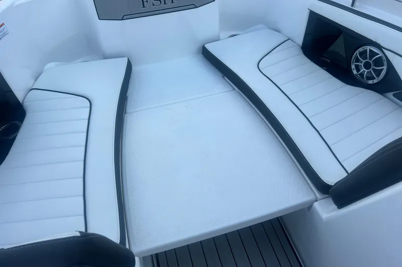 Slide: The Image of 2024 Yamaha Boats 255 FSH Sport H interior seating with sleek white cushions and speaker. - 26
