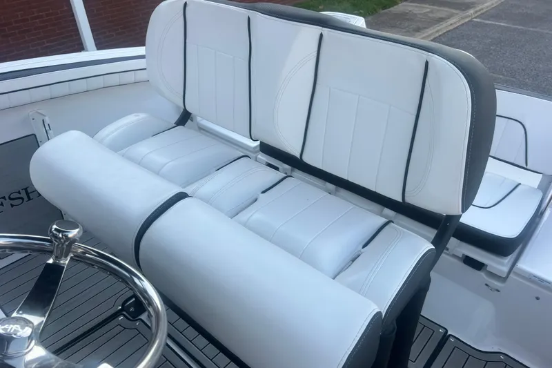 Slide: The Image of 2024 Yamaha Boats 255 FSH Sport H interior seating with white upholstery and steering wheel. - 44