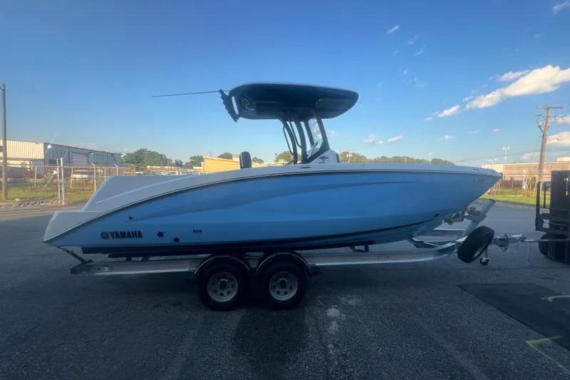 Slide: The Image of 2024 Yamaha Boats 255 FSH Sport H on trailer, side view under clear sky. - 52