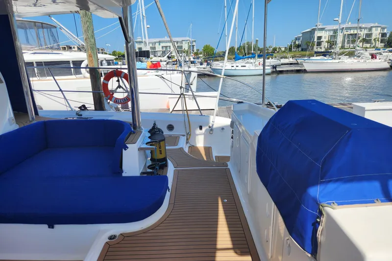 Slide: The Image of 2021 Royal Cape Catamarans Majestic 570 docked, featuring blue seating and wooden deck. - 16