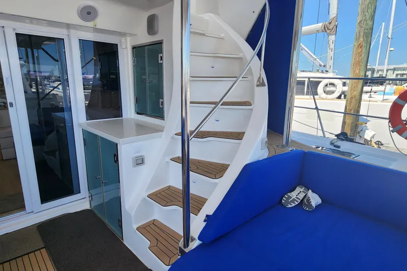 Slide: The Image of Interior of 2021 Royal Cape Catamarans Majestic 570 with spiral staircase and blue seating. - 24