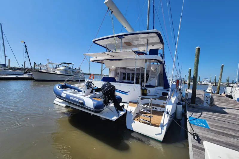 Slide: The Image of 2021 Royal Cape Catamarans Majestic 570 docked with inflatable boat, clear blue sky. - 3