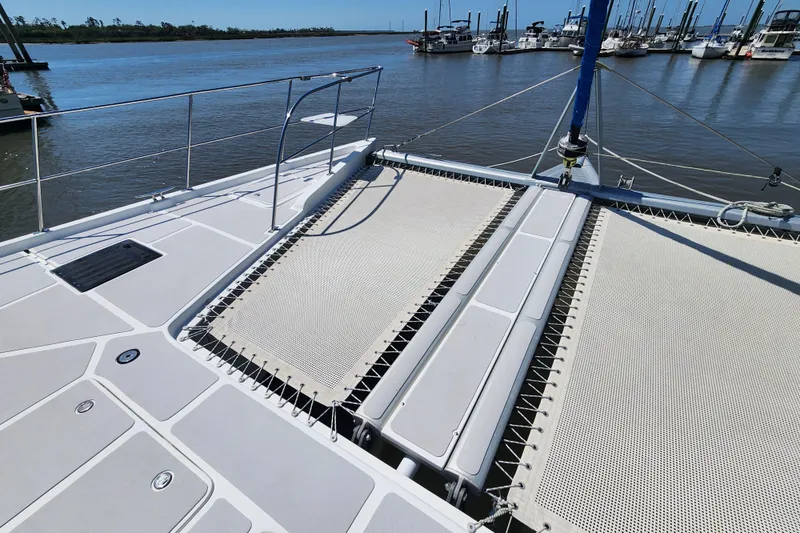 Slide: The Image of Deck view of 2021 Royal Cape Catamarans Majestic 570 at marina, featuring netted lounging area. - 46