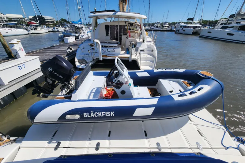 Slide: The Image of Catamaran Majestic 570 docked with inflatable boat, sunny marina setting. - 6