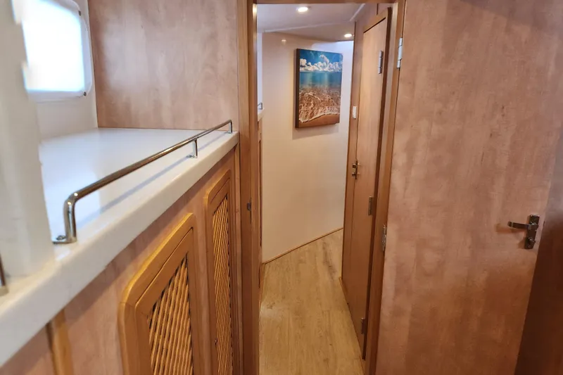 Slide: The Image of Interior hallway of 2021 Royal Cape Catamarans Majestic 570, featuring wooden finishes and artwork. - 85