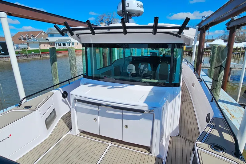 Slide: The Image of 2023 Axopar 37 XC Cross Cabin boat docked, showcasing sleek design and spacious deck. - 11