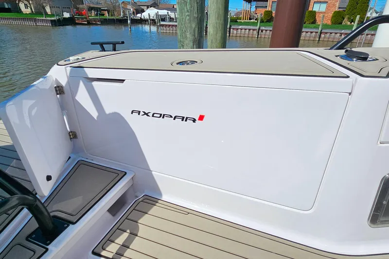 Slide: The Image of 2023 Axopar 37 XC Cross Cabin boat detail with logo, docked by waterfront homes. - 12