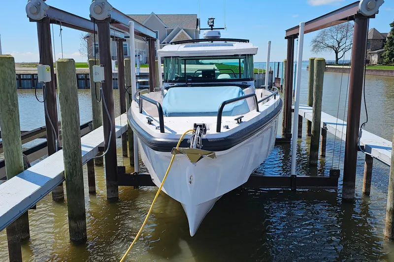 Slide: The Image of 2023 Axopar 37 XC Cross Cabin boat docked in a marina lift. - 2