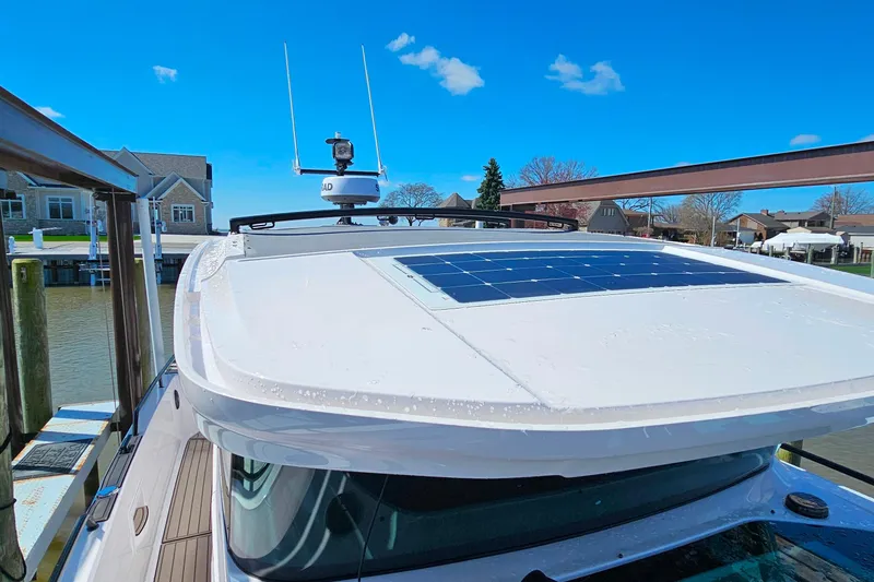 Slide: The Image of 2023 Axopar 37 XC Cross Cabin with solar panel on roof, docked by waterfront homes. - 30