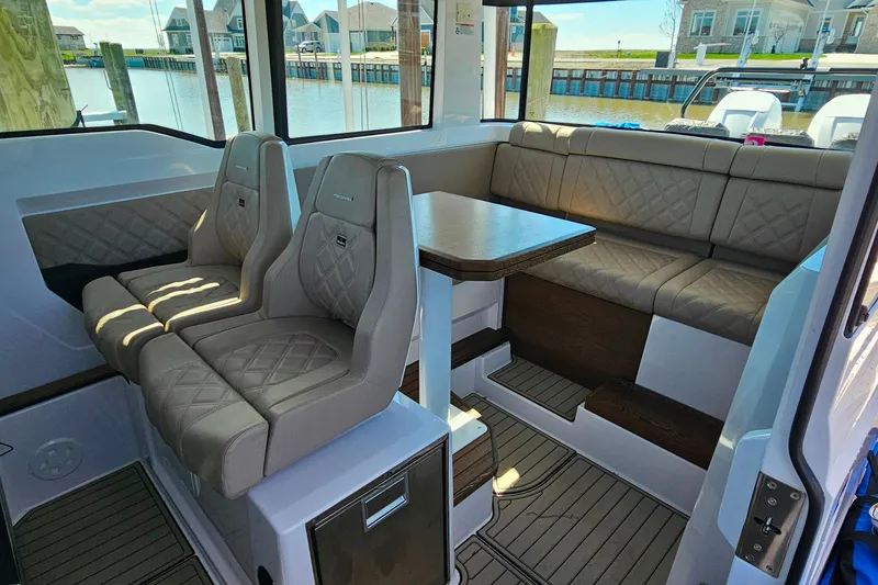 Slide: The Image of 2023 Axopar 37 XC Cross Cabin interior with seating and table, dockside view. - 31