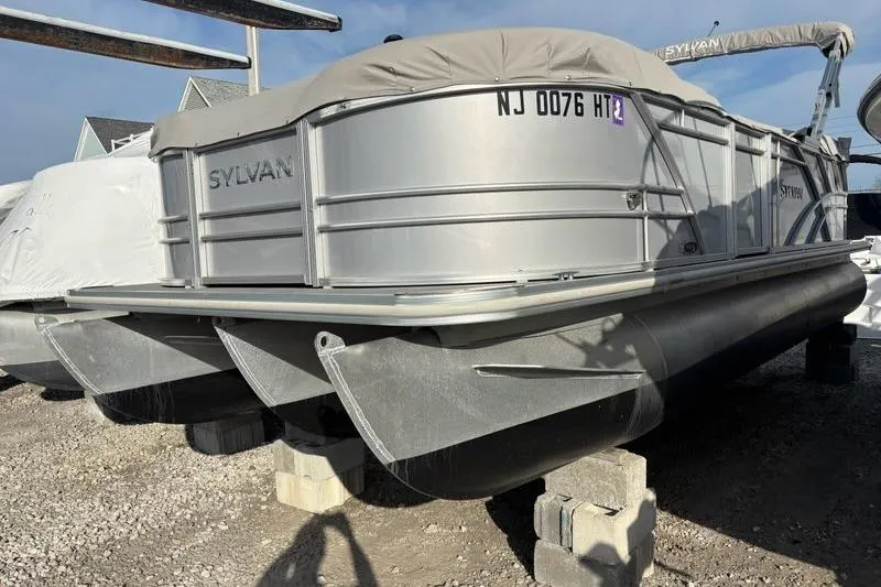 Slide: The Image of 2023 Sylvan Mirage 8522 LZ pontoon boat on blocks, covered and parked outdoors. - 2