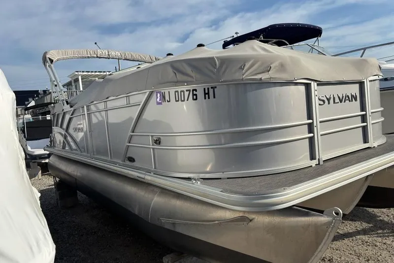 Slide: The Image of 2023 Sylvan Mirage 8522 LZ pontoon boat with cover, parked on gravel lot. - 3