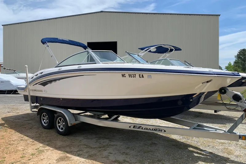 The Image of 2014 Chaparral 244 Sunesta boat on trailer, parked outdoors near a large building. - 0