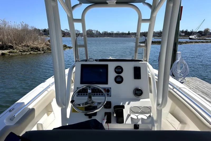 Slide: The Image of 2022 Key West 239 FS boat dashboard with steering wheel and navigation controls on calm water. - 2