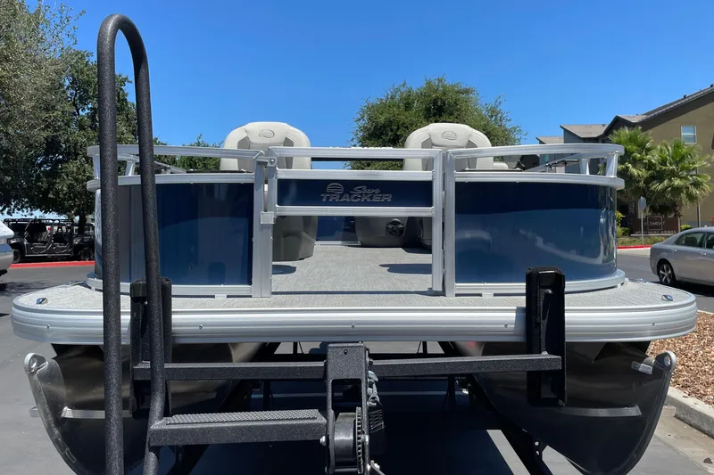 Slide: The Image of 2026 Sun Tracker Bass Buggy 16 XL Select pontoon boat on trailer, parked outdoors. - 4