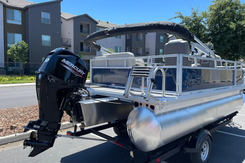 Slide: The Image of 2026 Sun Tracker Bass Buggy 16 XL Select pontoon boat with Mercury engine on trailer. - 2