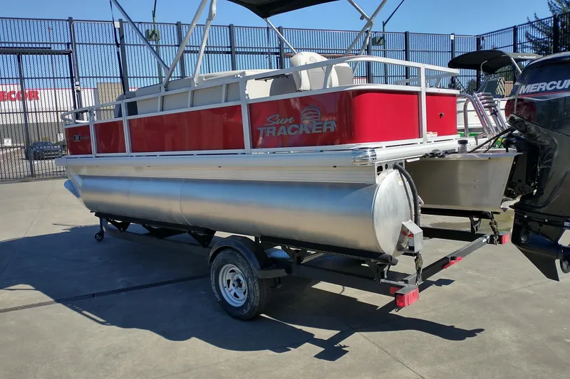 Slide: The Image of 2026 Sun Tracker Bass Buggy 18 DLX pontoon boat on trailer, red and silver design. - 3