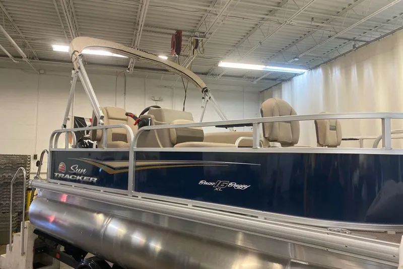 Slide: The Image of 2026 Sun Tracker Bass Buggy 16 XL Select pontoon boat in a showroom. - 5