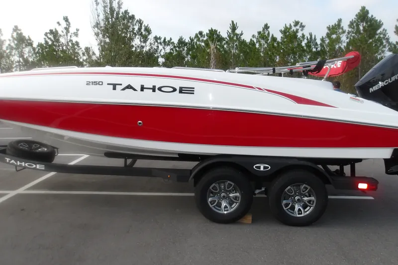 The Image of 2026 Tahoe 2150 boat in red and white on a trailer, parked outdoors. - 1