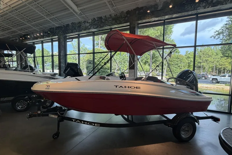 Slide: The Image of 2026 Tahoe T16 boat with red canopy displayed indoors, surrounded by large windows. - 1