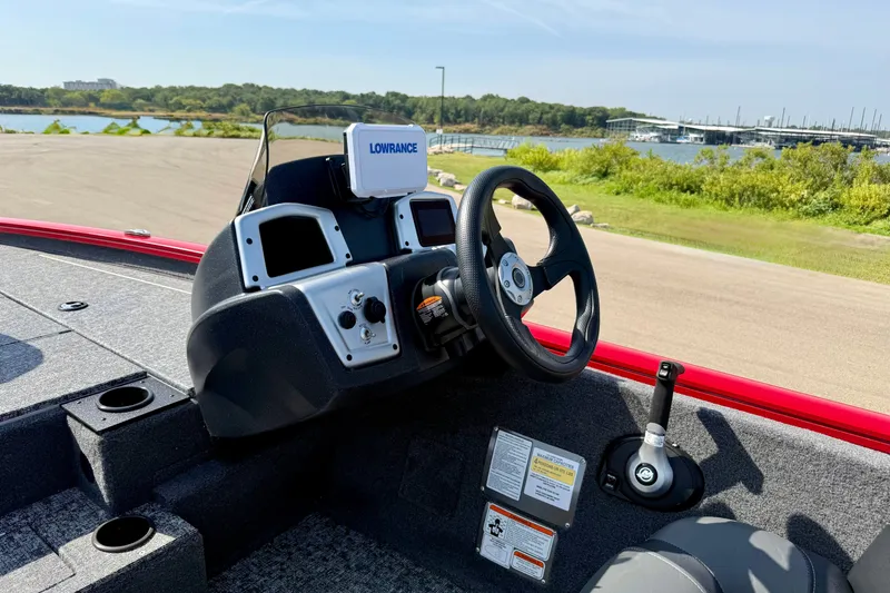 Slide: The Image of 2026 Tracker Pro Team 195 boat dashboard with Lowrance system, near a scenic lake. - 60