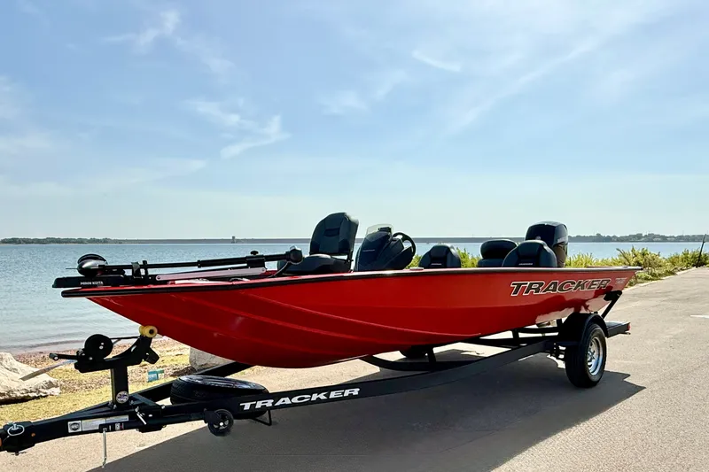 Slide: The Image of Red 2026 Tracker Pro Team 195 boat on trailer by a lakeside. - 67