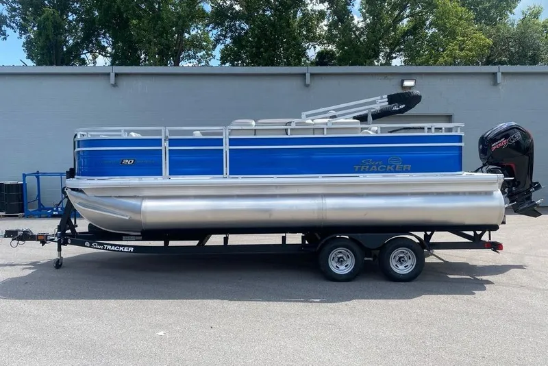 Slide: The Image of 2026 Sun Tracker Fishin' Barge 20 DLX pontoon boat on trailer, parked outdoors. - 1