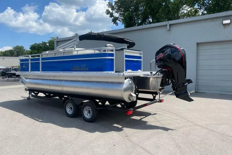 Slide: The Image of 2026 Sun Tracker Fishin' Barge 20 DLX pontoon boat on trailer, outdoors. - 2