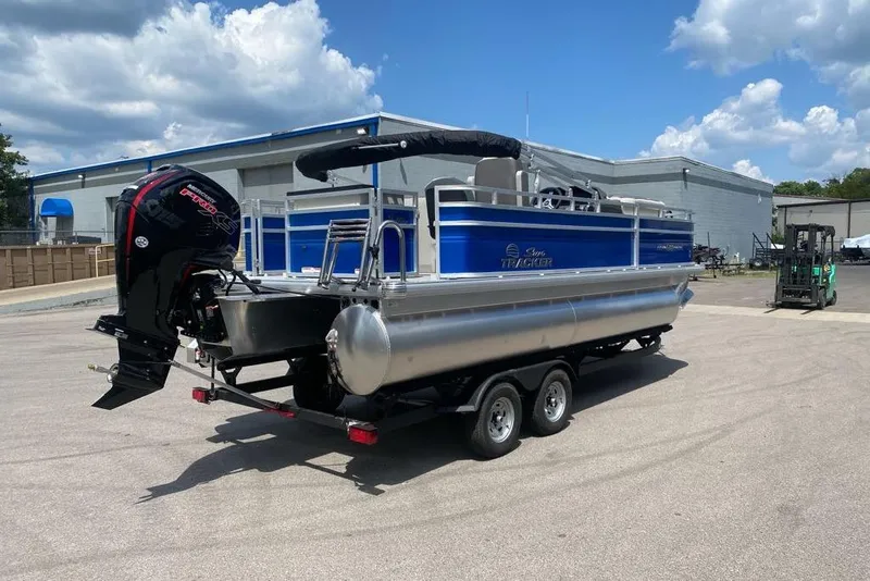 Slide: The Image of 2026 Sun Tracker Fishin' Barge 20 DLX pontoon boat on trailer, parked outdoors. - 3