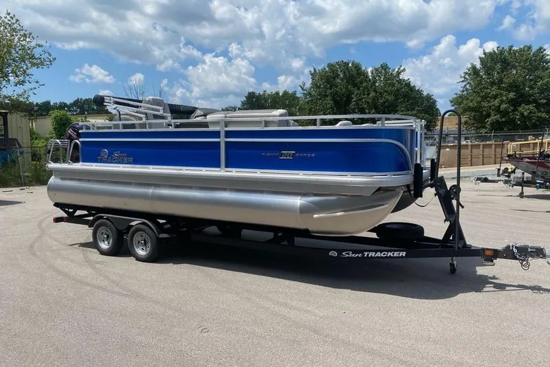 Slide: The Image of 2026 Sun Tracker Fishin' Barge 20 DLX pontoon boat on trailer under blue sky. - 6