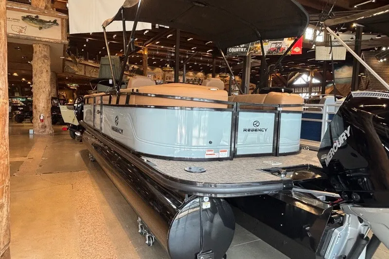 Slide: The Image of 2026 Regency 250 DL pontoon boat displayed indoors with Mercury engine. - 14