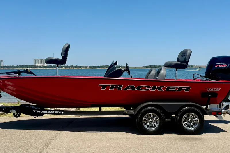 Slide: The Image of Red 2026 Tracker Pro Team 195 boat on trailer by a lake, clear sky background. - 22
