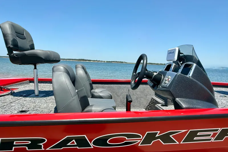 Slide: The Image of 2026 Tracker Pro Team 195 boat interior with steering console and seating, on a lake. - 2