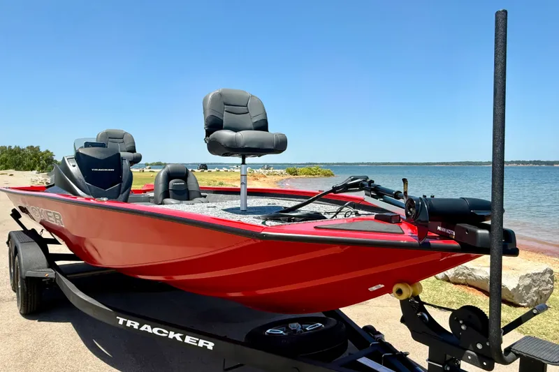 Slide: The Image of Red 2026 Tracker Pro Team 195 boat on trailer by a lake, featuring comfortable seating. - 5