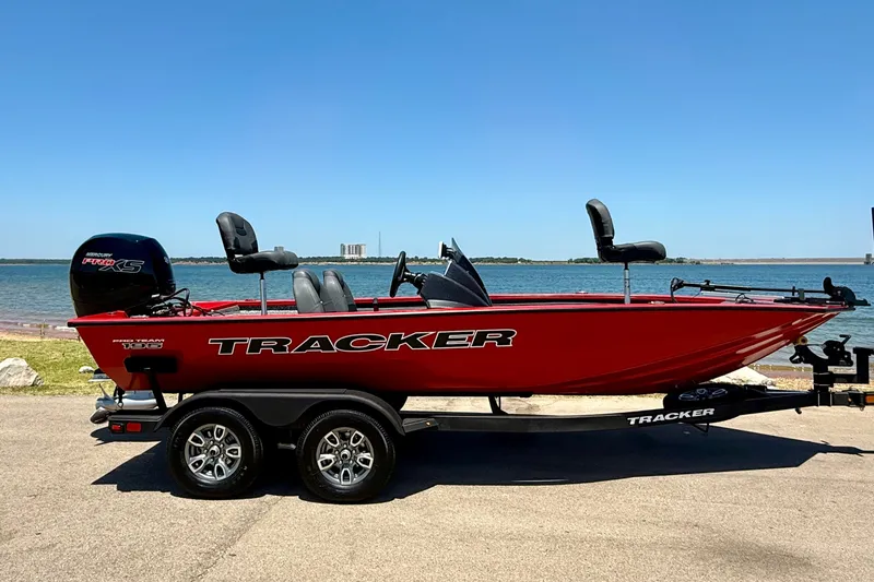 The Image of 2026 Tracker Pro Team 195 boat on trailer by the water, featuring a sleek red design. - 0