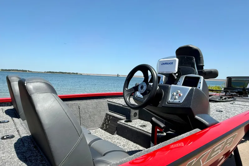 Slide: The Image of 2026 Tracker Pro Team 195 boat interior with steering wheel, seats, and Lowrance equipment by the water. - 3